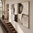 Black Curved Shapes on Cream Diptych Wall Art shown beside a staircase.