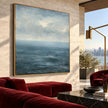 Blue Sea and Soft Cloud Horizon Wall Art shown above a red sofa.