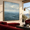 Blue Sea and Soft Cloud Horizon Wall Art shown above a red sofa.