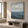 Blue Sea and Soft Cloud Horizon Wall Art shown above a stone-colored bench.