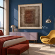 Brown Stacked Ridges on Taupe Wall Art shown above a bed beside a yellow chair.