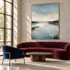 Misty Blue Lake with Reeds Wall Art shown above a burgundy sofa.
