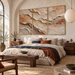 Ochre and Ivory Strata Triptych Wall Art shown above a bed with a rust-colored throw.