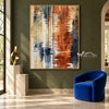 Rust and Navy Water Reflection Abstract Wall Art shown beside a blue chair on a green wall.