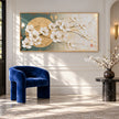 White Blossoms across a Golden Circle Wall Art shown above a blue chair and a side table.