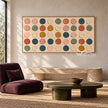 Wide Multicolor Painted Dot Grid Wall Art shown above a pale bench behind a round coffee table.